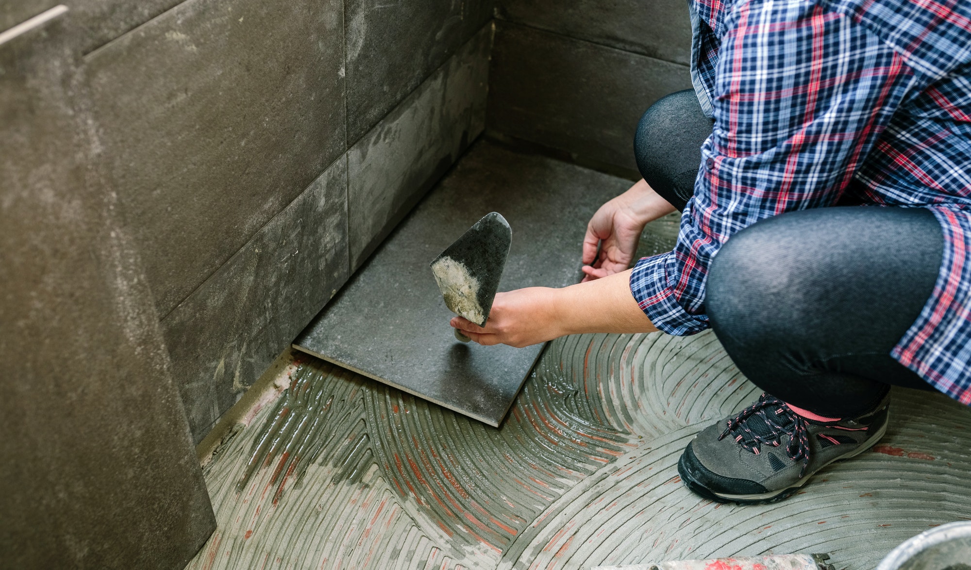 female manual worker laying a new tile floor